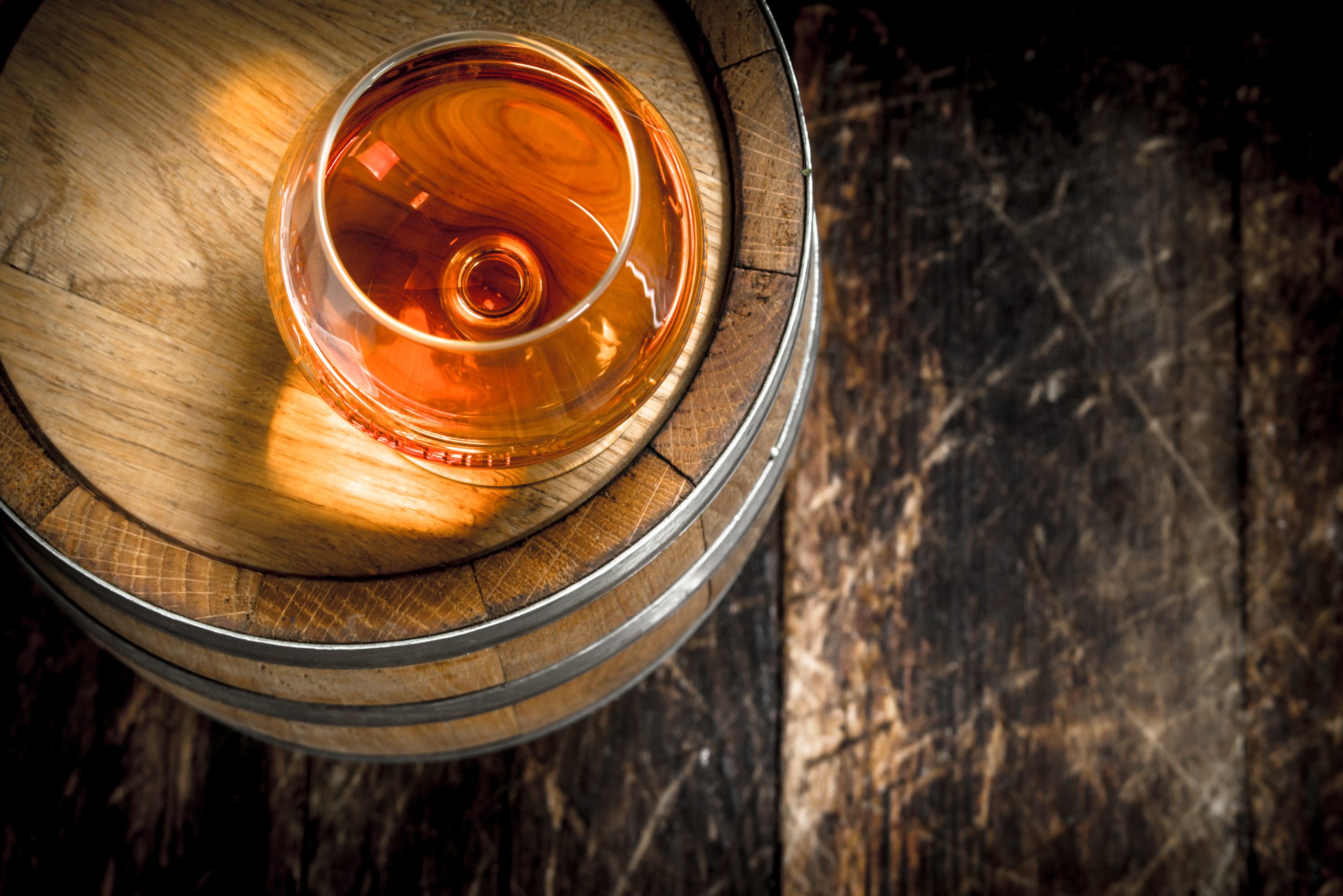 barrel with a glass of cognac. On a wooden background.